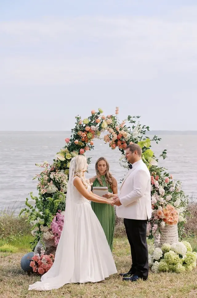 A ceremony beneath a floral arch at the water's edge at 11 Mile.