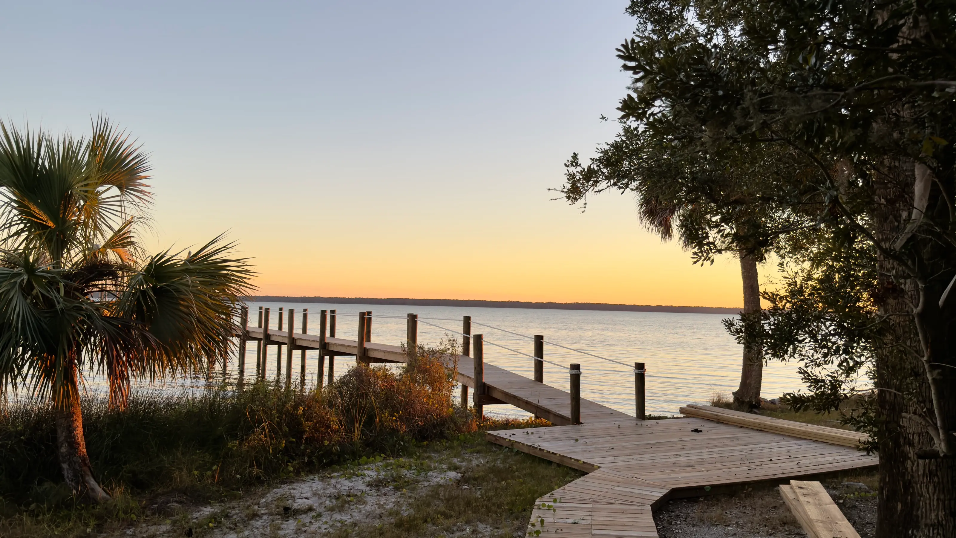 The dock at 11 Mile reaching into St. Vincent Sound at sunset, under palms and live oak.