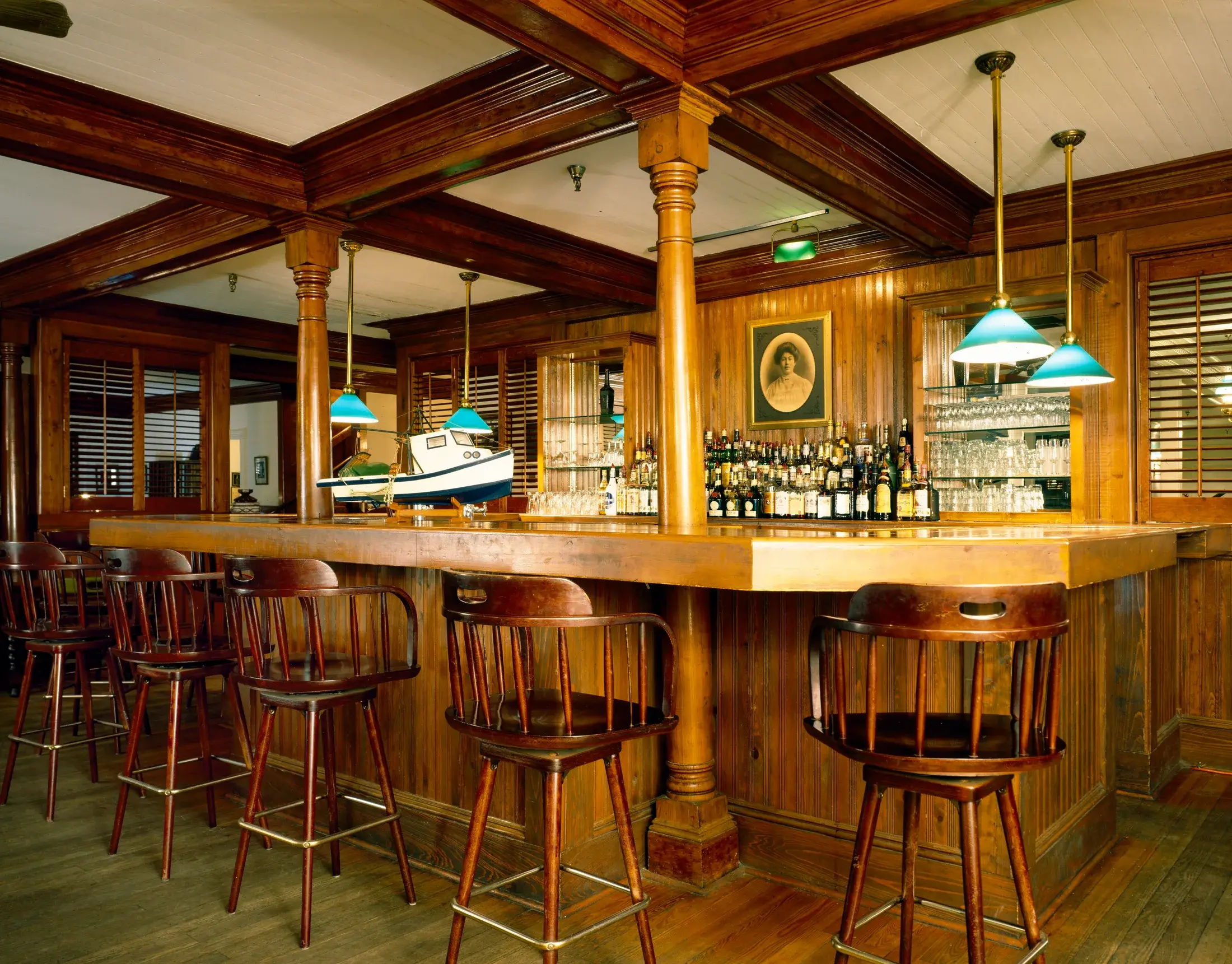 The bar at the Gibson Inn: a long counter and columns in varnished pine under a beamed ceiling, with green glass pendant lights.