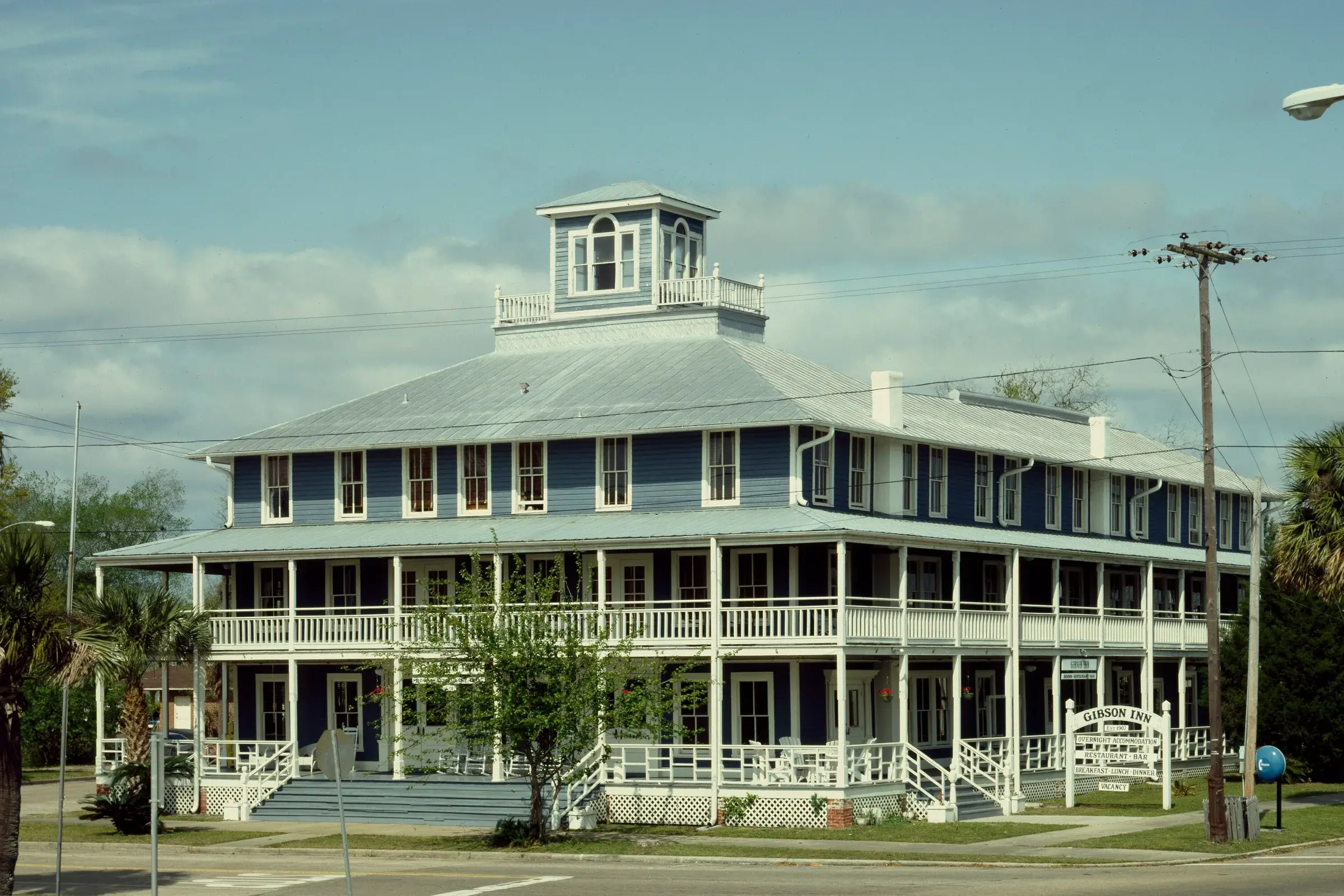 The Gibson Inn in Apalachicola: a three-story blue clapboard hotel of 1907 with white wraparound porches and a rooftop cupola.