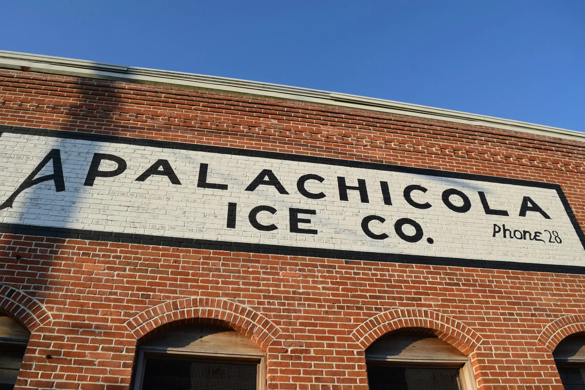 The brick facade of the Apalachicola Ice Company, its hand-painted sign still reading Phone 28.