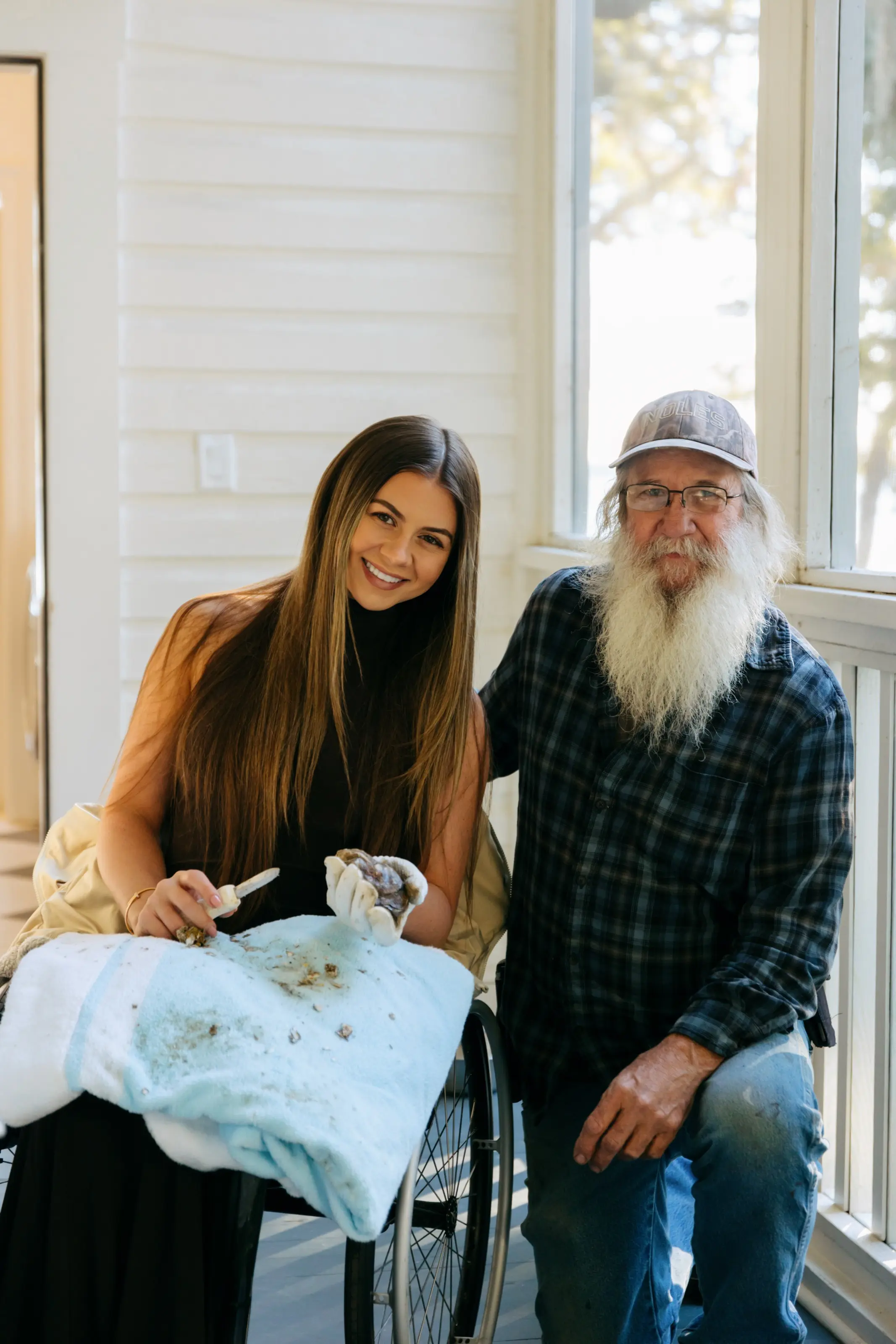 Kendall Schoelles shucking oysters on the screened porch at 11 Mile, with owner Megan McGill seated beside him.