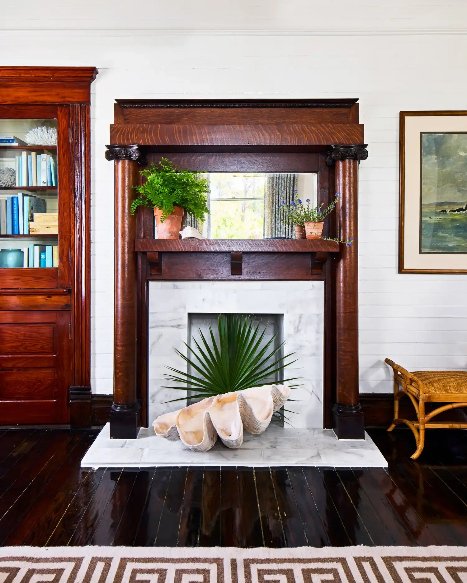A carved mantel and marble firebox in the restored house, with an overmantel mirror.